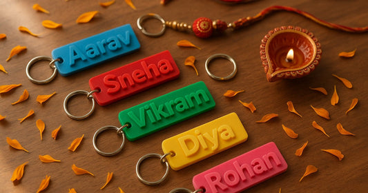 3D printed personalized name keychains arranged with a Rakhi thread and marigold petals for Raksha Bandhan gifting