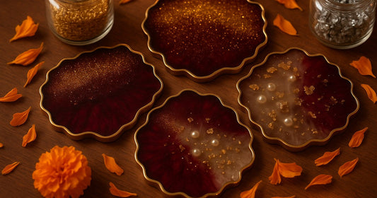 Resin coasters with gold glitter and metallic flakes suspended mid-layer, surrounded by resin art inclusions on a wooden surface with warm festive lighting