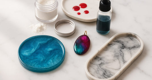 Mica powder, alcohol ink, and resin dye displayed next to finished resin coaster, jewelry pendant, and marble-effect tray