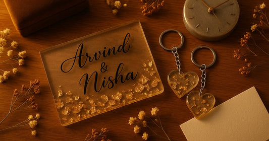 Personalized resin anniversary gifts for Indian couples including a gold leaf name plaque, matching keychains, and a silver resin clock arranged on a wooden surface