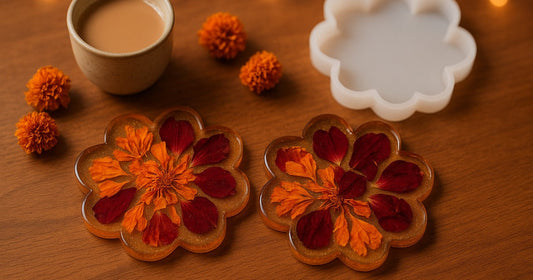 Handmade resin flower coasters with embedded dried marigold and rose petals, gold mica shimmer base, displayed on wood with chai cup and diya for Diwali gifting