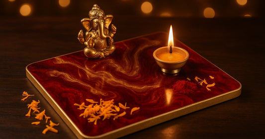 Handmade resin pooja thali with gold mica swirls and red pigment, decorated with a Ganesh figurine and a lit diya for Diwali