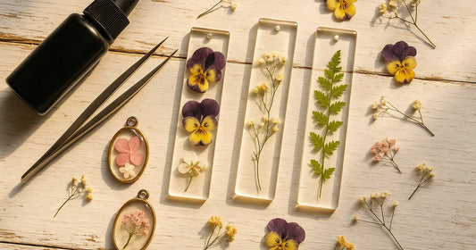 UV resin dried flowers bookmarks and pendants with pressed pansies and baby's breath on a white wooden surface
