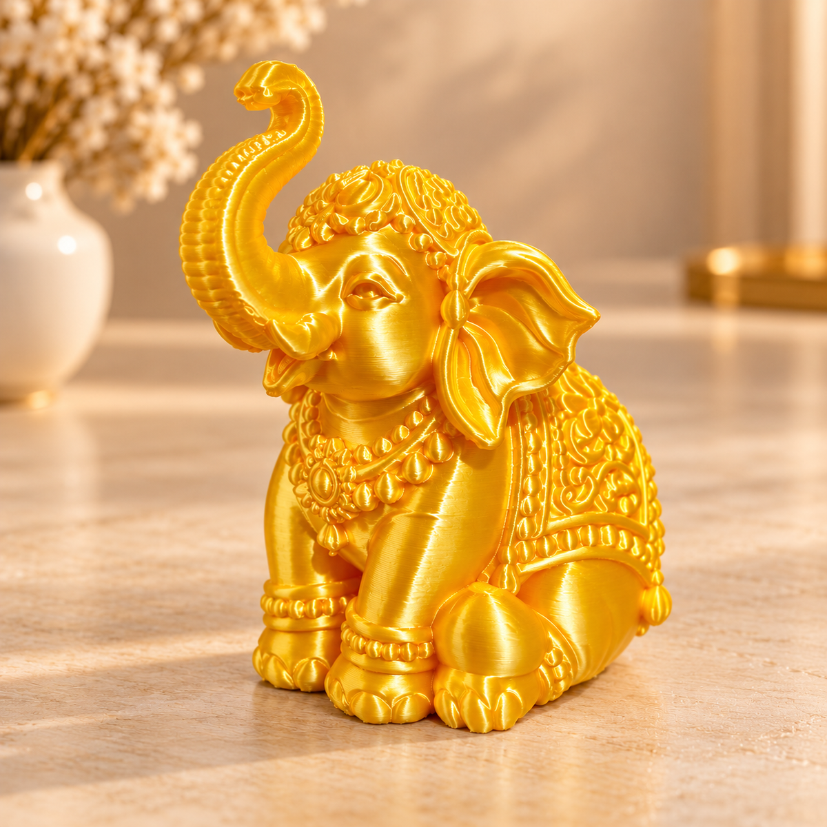 Golden elephant 3D printed miniature in silk gold PLA finish on a white surface, side view showing detailed trunk-up pose